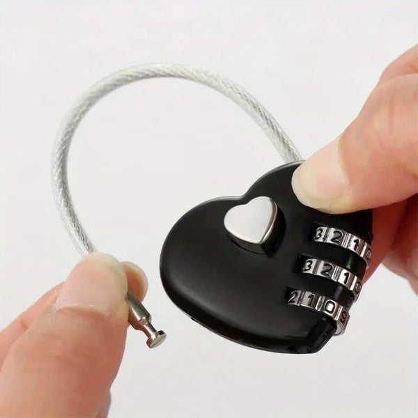 A hand holds a compact heart-shaped combination padlock with a silver wire and numbered dials.