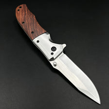 A premium folding utility pocket knife with a dark wood handle and polished silver blade resting on a black surface.