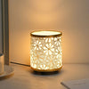 A minimalist desk lamp with a woven fabric shade emits a warm glow on a white surface.