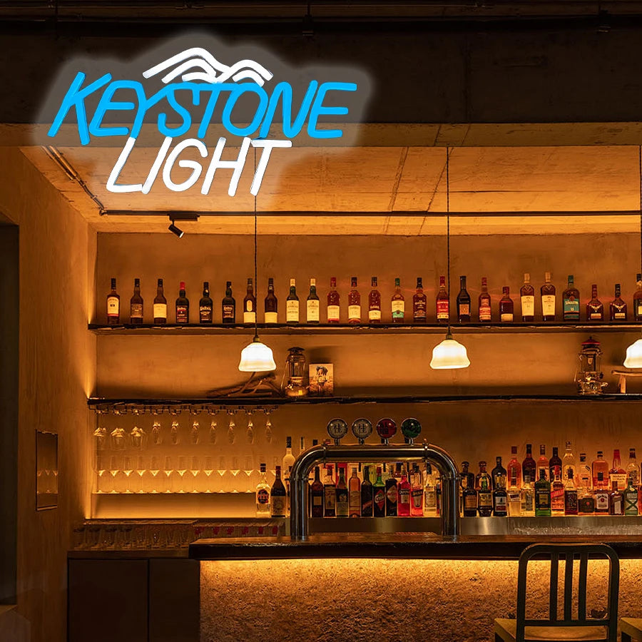 لقطة مقربة لعلامة نيون تضيء رفّاً خشبياً للزجاجات والأكواب، مكتوب عليها KEYSTONE LIGHT.