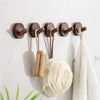 Rustic wooden wall hooks displaying a bamboo brush and a white towel on a marble surface