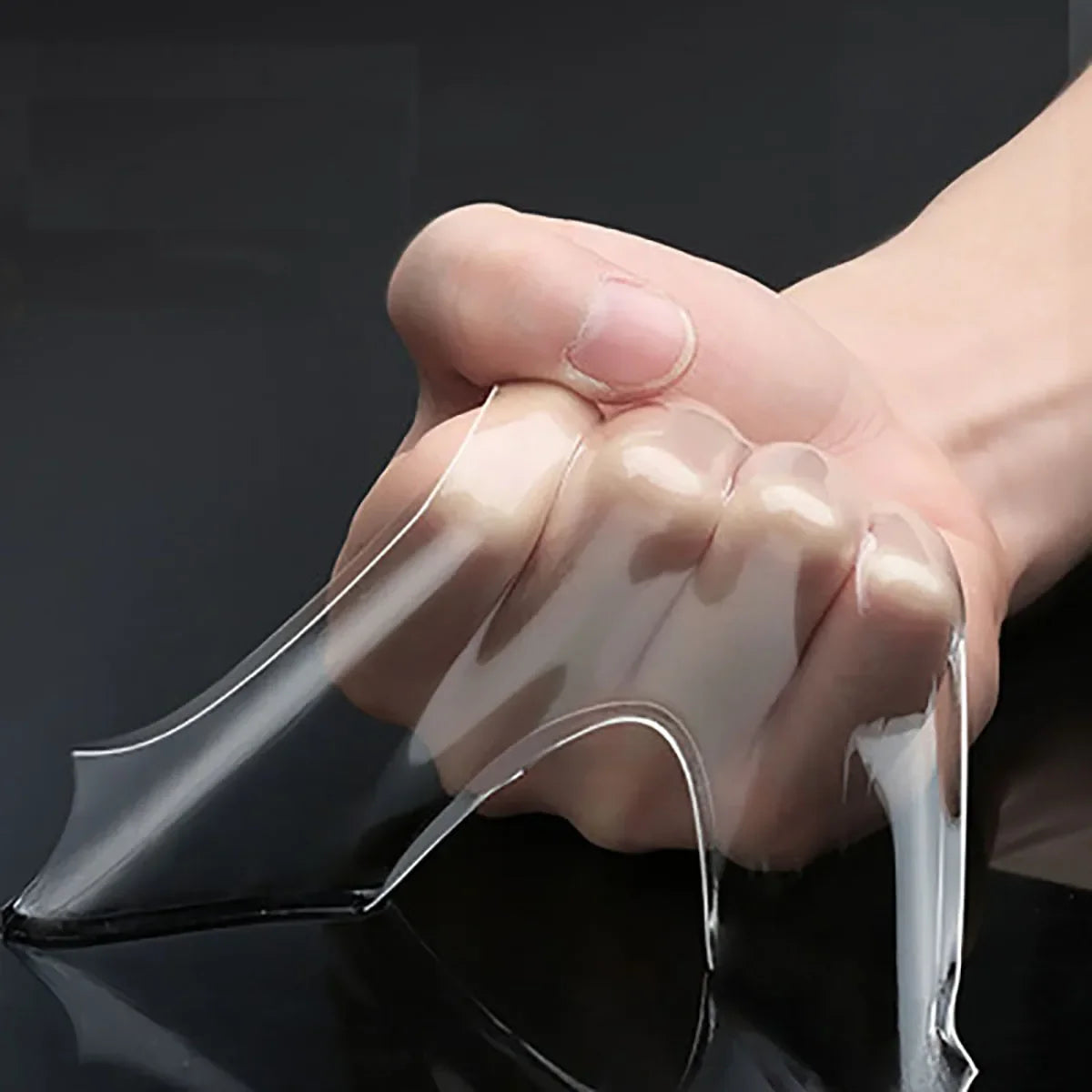 A hand is applying clear double-sided mounting tape to a dark surface.