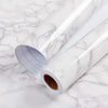 Roll of glossy pink marble contact paper lying on a white marble surface