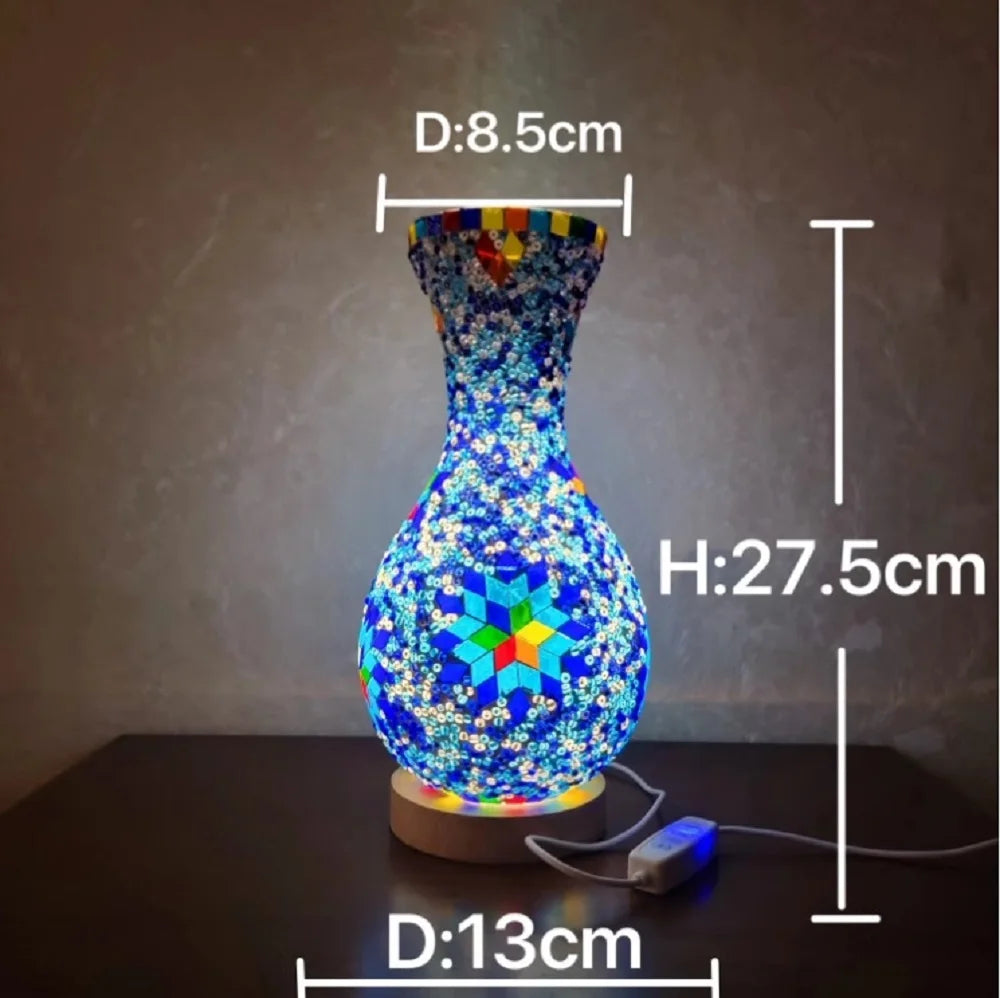 Una lámpara de vidrio azul vibrante con un patrón de mosaico multicolor sobre una base de madera.