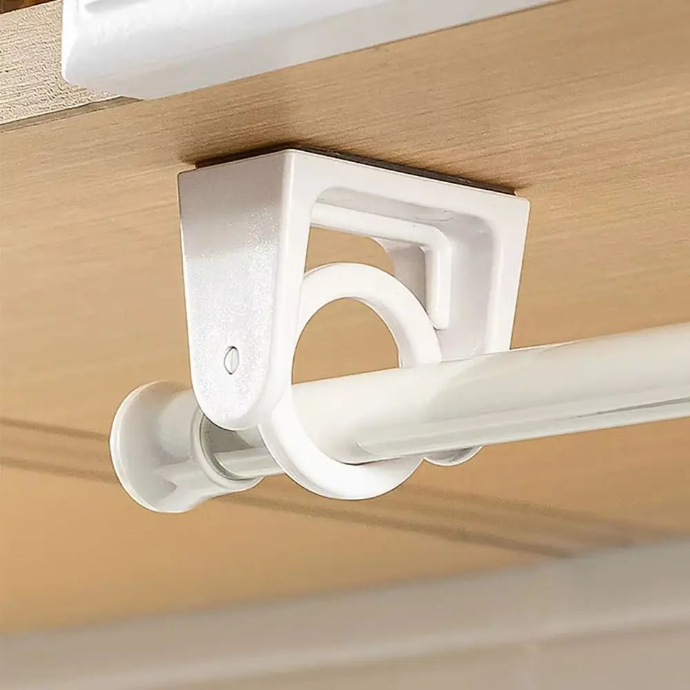 White rotating adhesive curtain rod brackets mounted on a ceiling, used to support a white curtain rod.