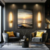 Dos apliques de pared dorados modernos iluminan una sala de estar con muebles gris oscuro y vista al atardecer.
