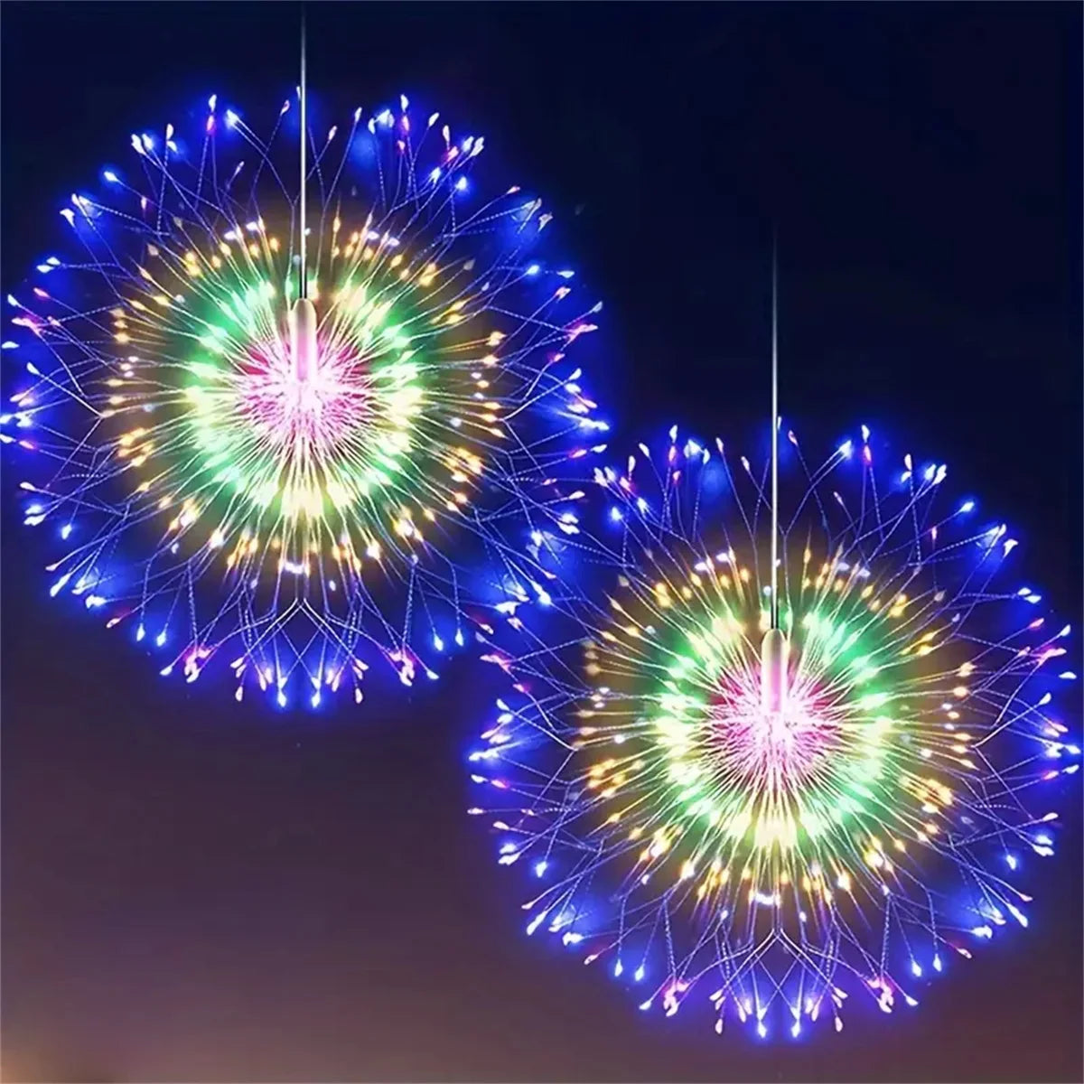 Two bright fireworks displays of blue and green lights against a dark night sky