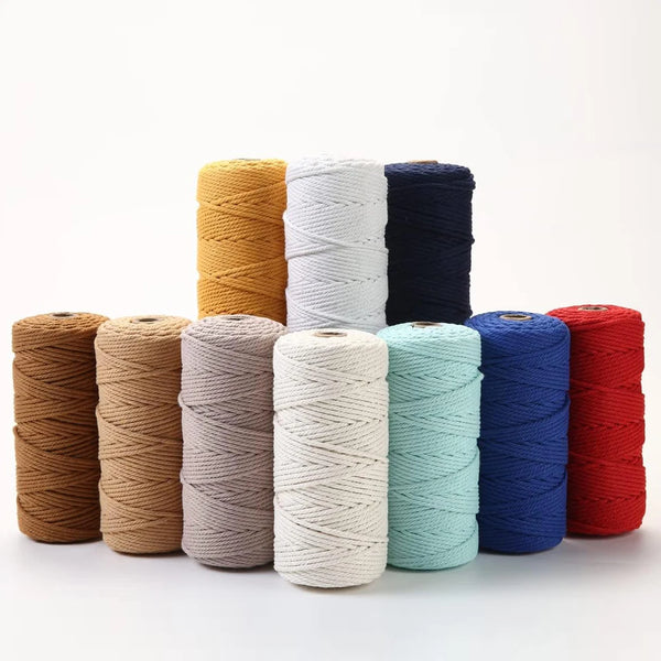 A collection of spools of 100m natural cotton macrame cord in various shades including beige, white, blue, and red.