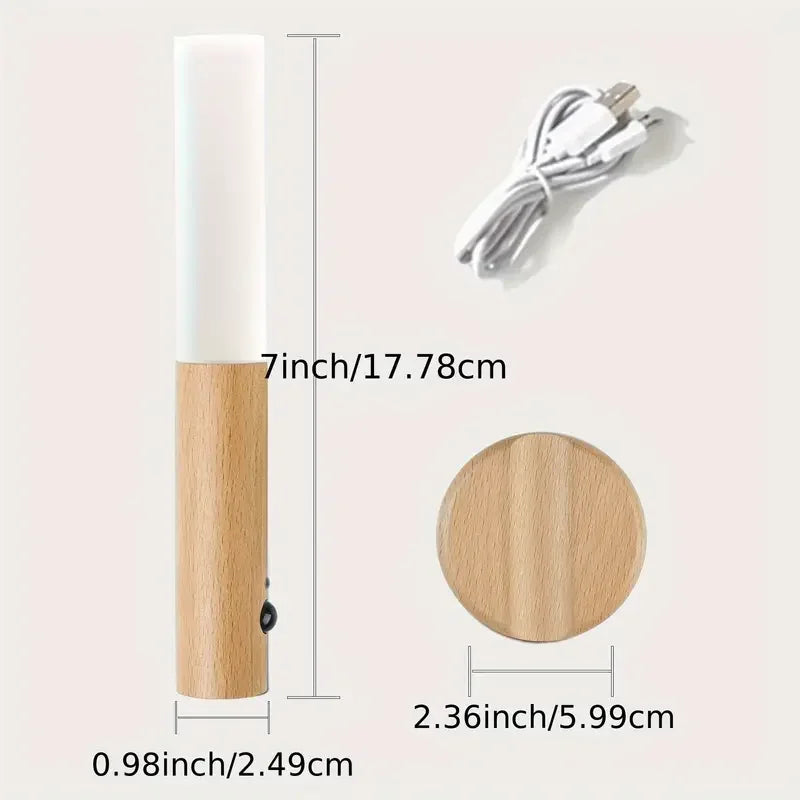 Luz nocturna de madera con luz LED cilíndrica blanca y cable, junto a su base circular.