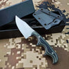 A fixed blade utility knife with a dark green handle and silver blade is displayed in a black box on a camouflage background.
