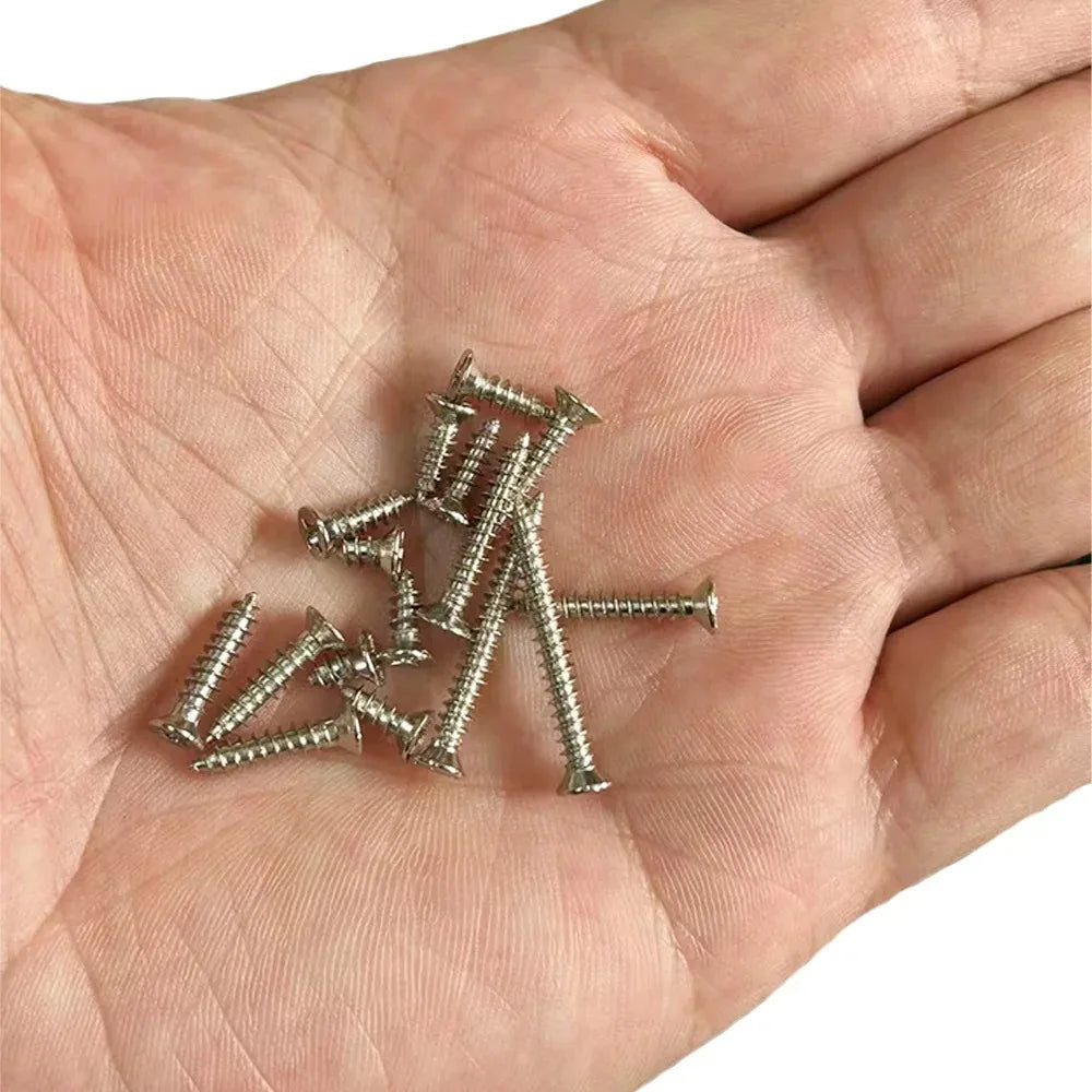 A hand holds a small set of silver precision self-tapping wood screws.