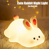 A white rabbit silicone night light with glowing eyes resting on a fluffy surface.