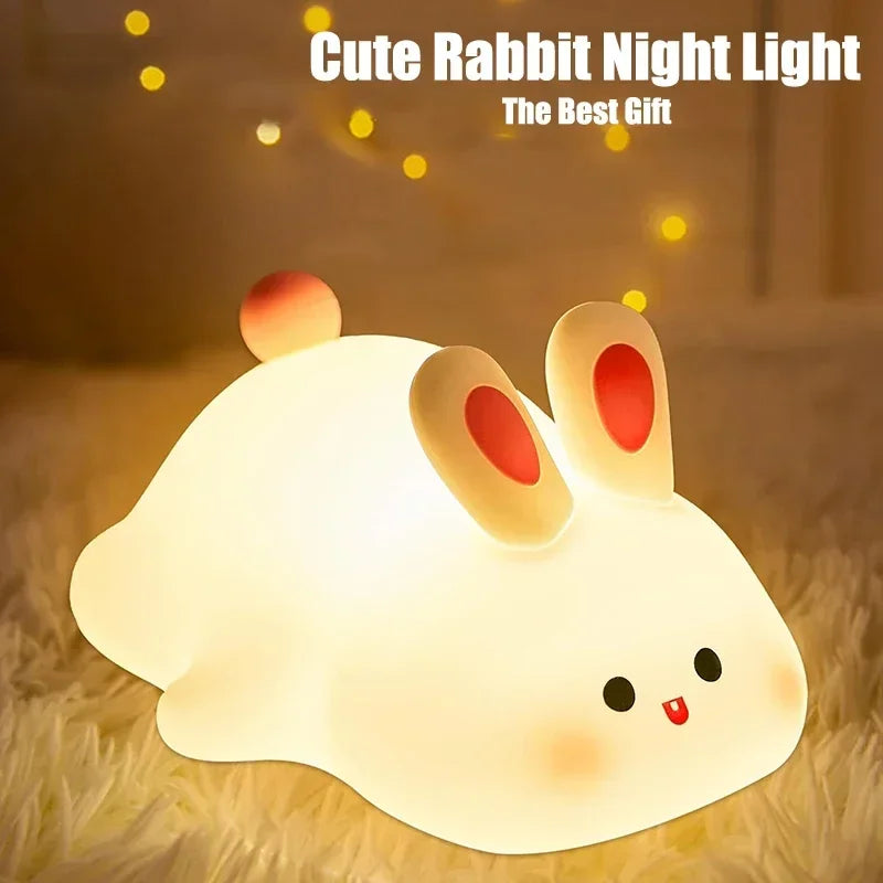 A white rabbit silicone night light with glowing eyes resting on a fluffy surface.