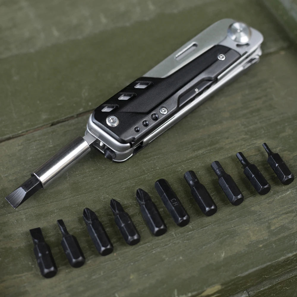 A silver compact multi-tool pocket knife with a blade and several interchangeable tools laid out on a wooden surface.