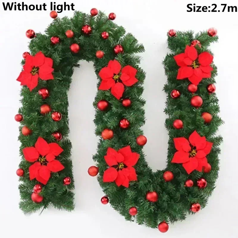 Green artificial pine garland with red berries and red flowers, without light.