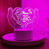 A glowing heart-shaped night light featuring a silhouette of a mother and child, set against a pink background.