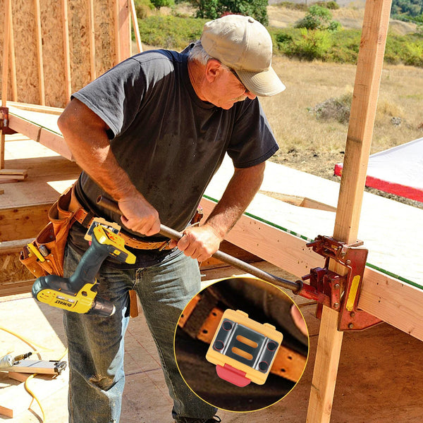 A man is using an adjustable tape measure holder tool on a piece of lumber during construction work.