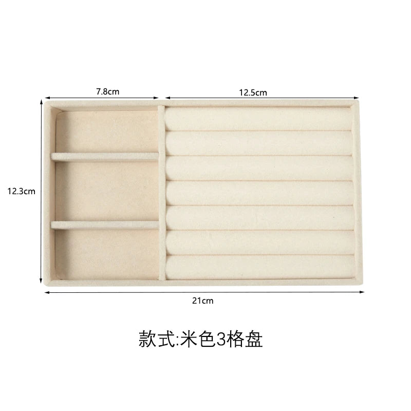 A rectangular beige jewelry storage tray with three compartments and a ribbed design.