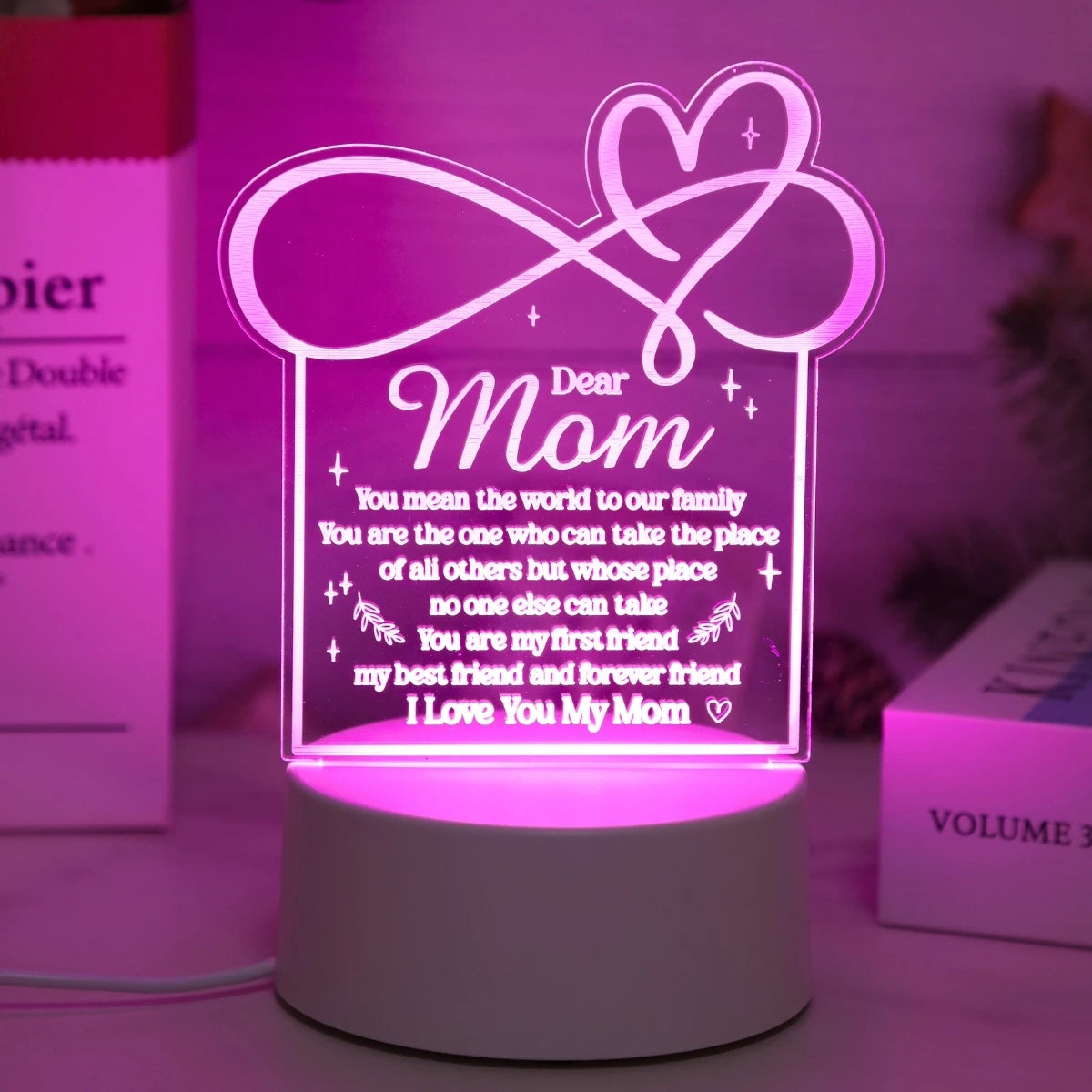 A glowing pink heart-shaped sign light featuring a message to mom on a white base.