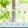 A set of realistic dragonfly clips used for garden decor displayed on a white wooden surface.