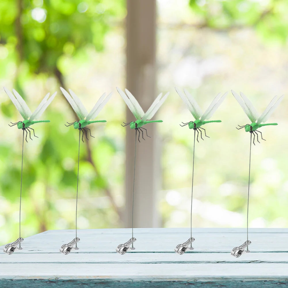 A set of realistic dragonfly clips used for garden decor displayed on a white wooden surface.