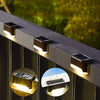 Close-up of solar LED outdoor lights mounted on a deck railing, showing the light beam and installation detail.