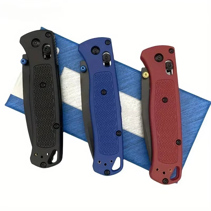 Trois couteaux pliants à poches noirs, bleus et rouges sont exposés sur un tissu rayé bleu et blanc.