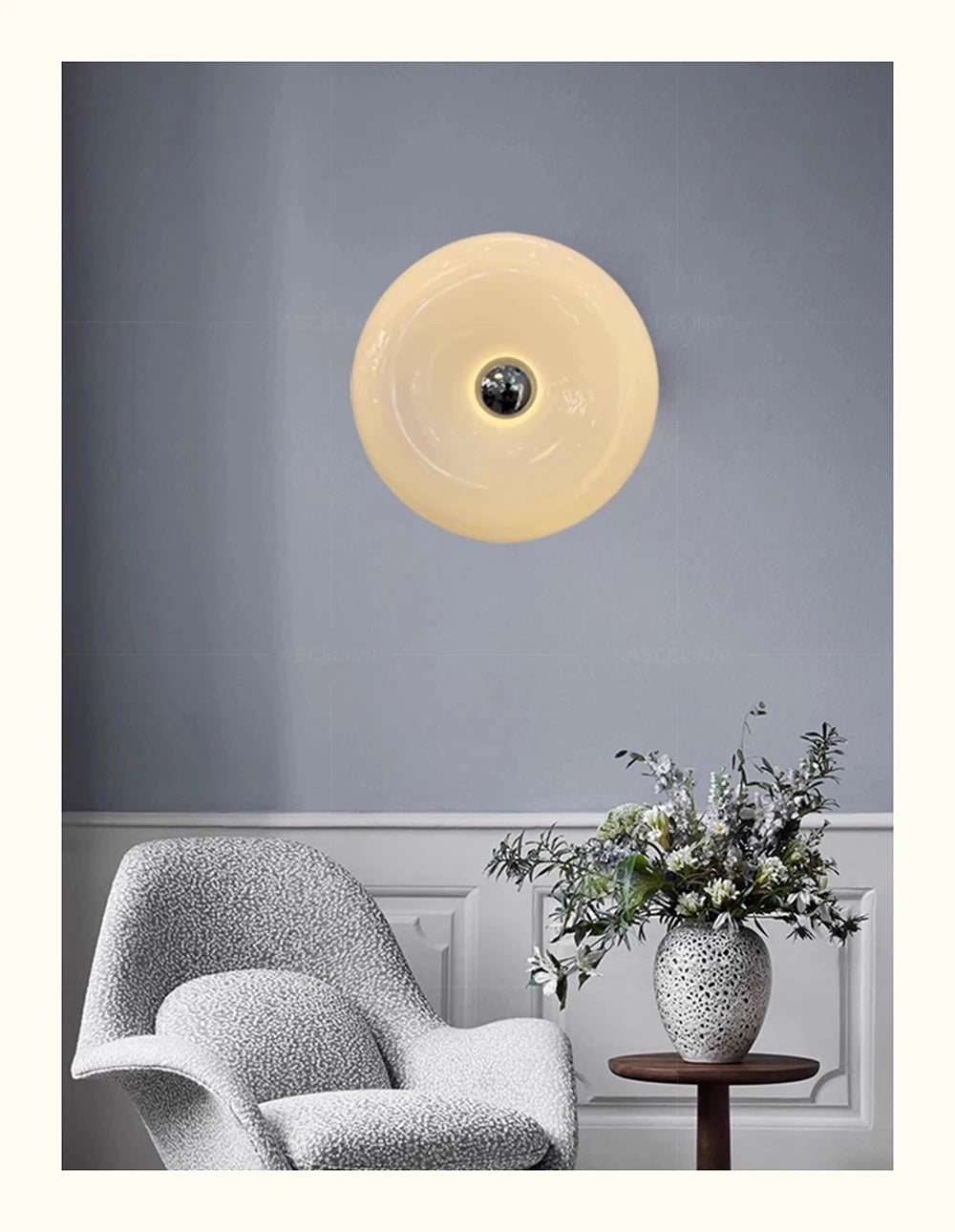 Runde, blassgelbe LED-Wandleuchte mit Donut-Design, montiert an einer grauen Wand über einem weißen, bezogenen Stuhl.
