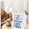 Termómetro digital y medidor de humedad blancos mostrando 25.0 °C y 60% de humedad, sobre una mesa de madera.