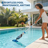 A woman is using a cordless handheld pool vacuum cleaner to clean water in a swimming pool.