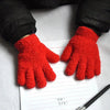 A pair of bright red plush full finger winter gloves resting on lined paper.