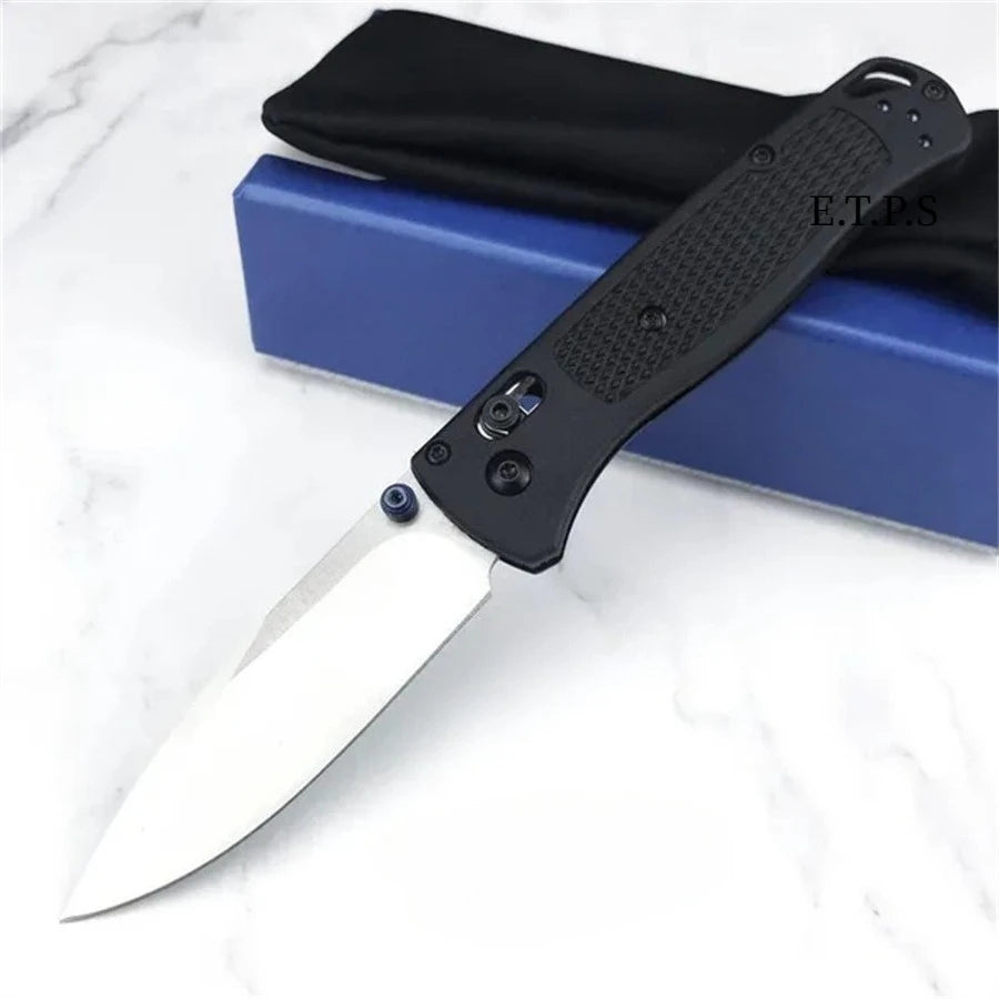Un couteau de pliage EDC noir avec une lame argentée est posé sur une surface bleue.