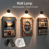 A wall lamp with a magnetic spotlight and touch control features is mounted on a wall above framed artwork.
