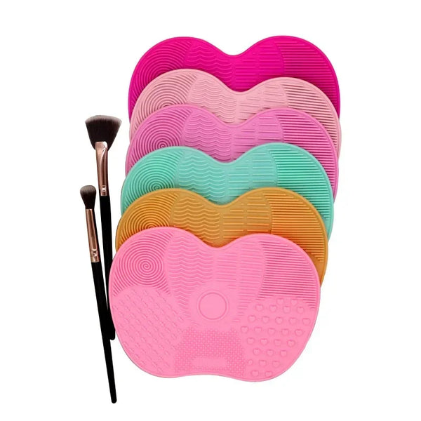 A set of five silicone makeup brush cleaning mats in various shades of pink and green.