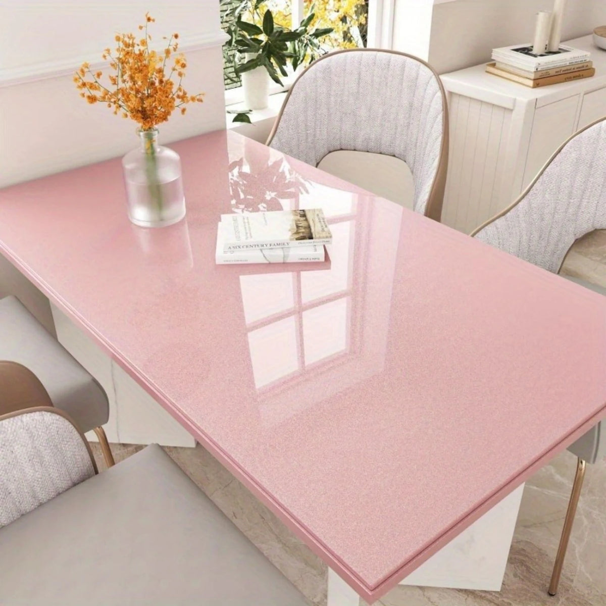A glossy pink marble tabletop with a vase of dried yellow flowers and surrounding light-colored chairs.