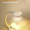 A small, flexible clip light illuminates a page of a book for reading at night.