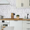 White marble backsplash with light wood countertop and cream shaker cabinets.