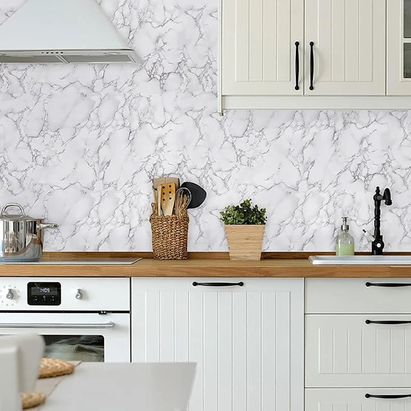 White marble backsplash with light wood countertop and cream shaker cabinets.