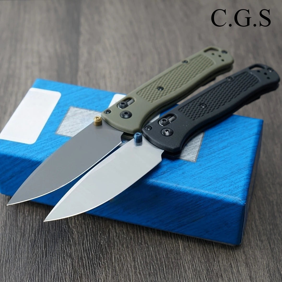 A folding pocket knife with a green handle and black blade is displayed on a blue box.