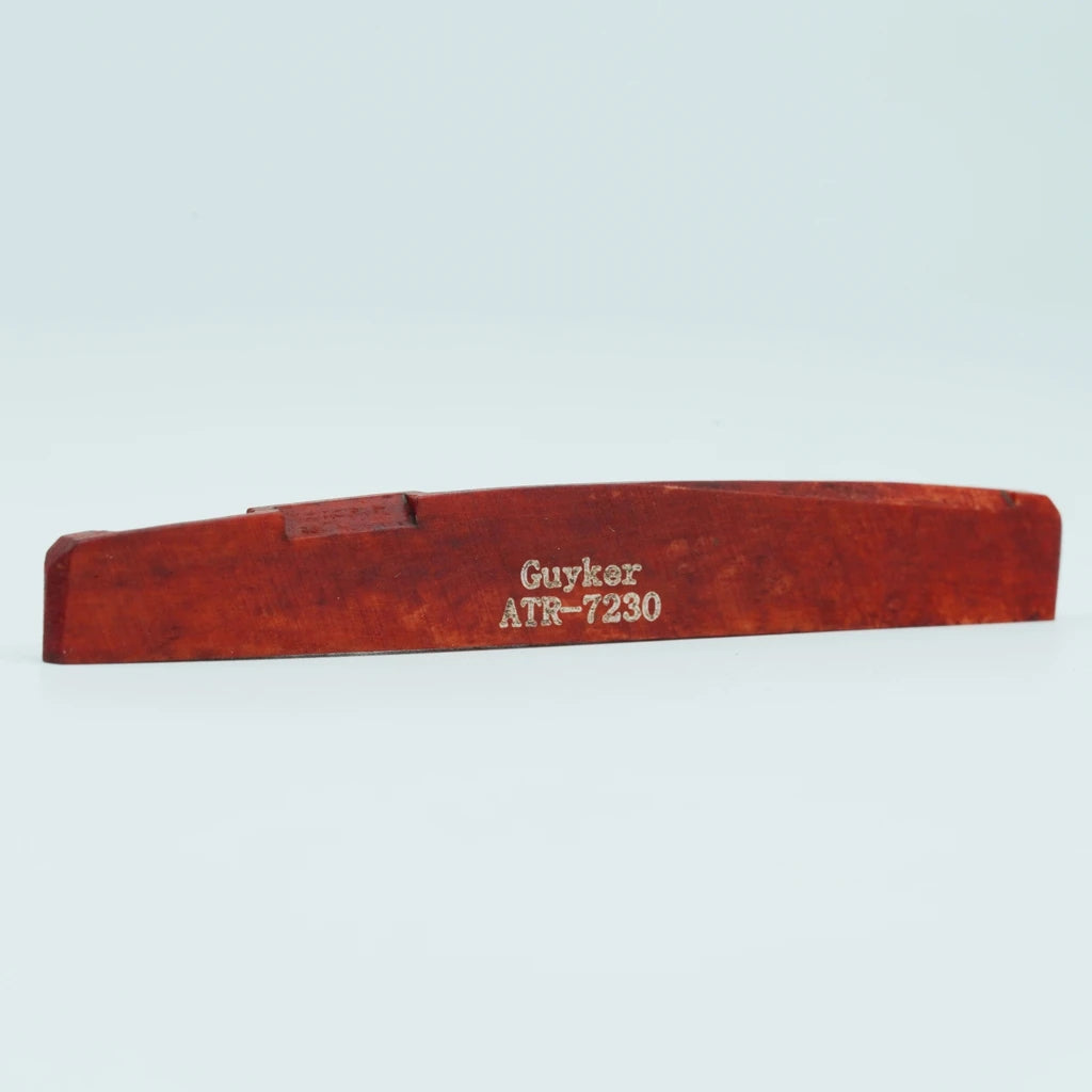 A wooden guitar bone bridge saddle with the name Guyker ATR-7230 engraved on it.