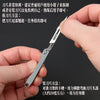 A hand holds a mini folding art knife demonstrating its use for cutting paper.