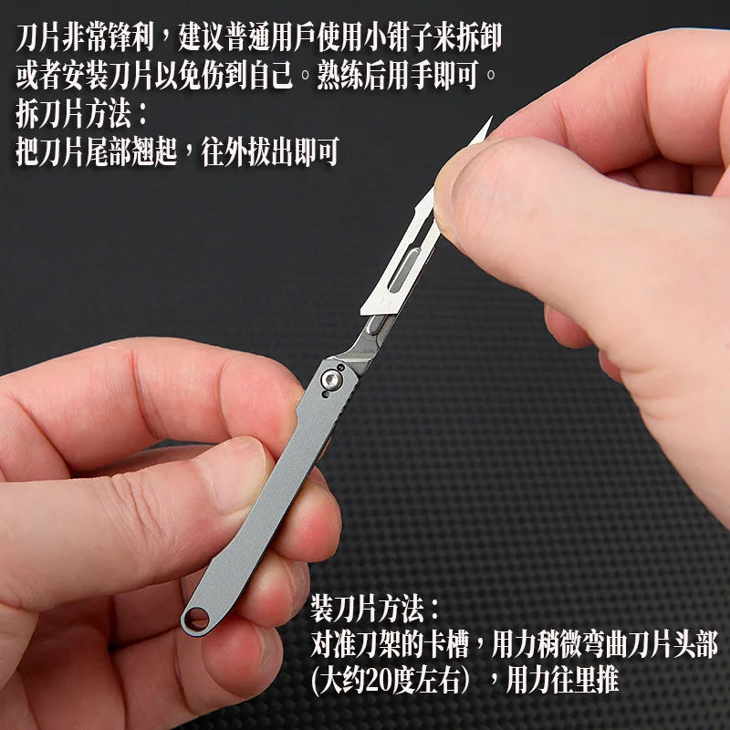 A hand holds a mini folding art knife demonstrating its use for cutting paper.