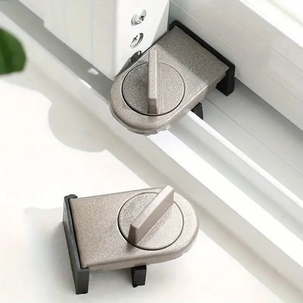 A close-up view of a silver aluminum sliding window safety lock mechanism mounted on a white frame.