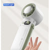 A hand is holding a white and light green portable handheld fan with a digital display.
