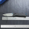 A carbon fiber folding knife blade and handle are shown resting on a ruler against a dark gray background.