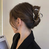 A close-up of a woman's hair styled in an updo with elegant gold S-shaped metal hair clips.