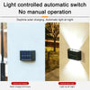 A black solar wall light is mounted on a white surface, illuminating the area at night.