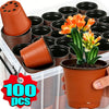 A hand holds a terracotta-colored plastic nursery pot, surrounded by stacks of black and orange two-color seeding pots.