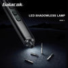 A close-up view of a metallic LED shadowless lamp tool and several precision screwdriver bits on a dark surface.