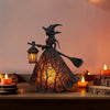 Linterna gótica de bruja de metal oscuro, luz nocturna con sombrero puntiagudo y luz ámbar brillante, sobre una superficie de